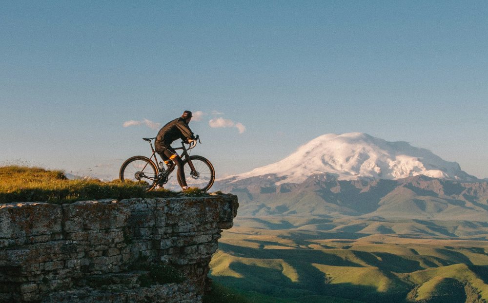Ciclista en el monte divisando una montaña nevada tras llevar a cabo sus hábitos de vida saludables | Farmacia Labandeira