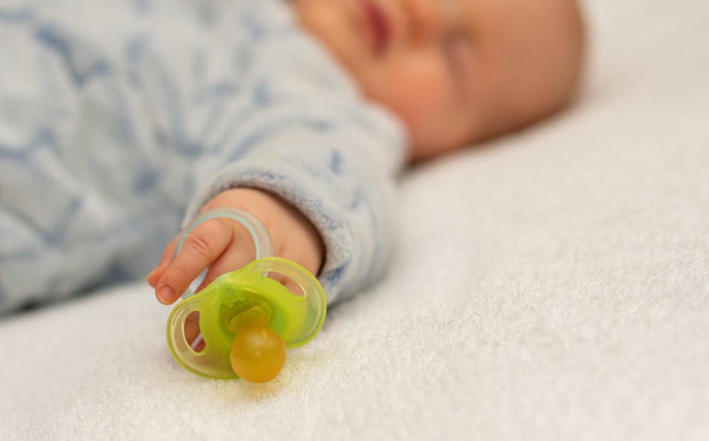 bebé durmiendo con chupete en la mano luego de elegir chupete idóneo. | Farmacia Labandeira